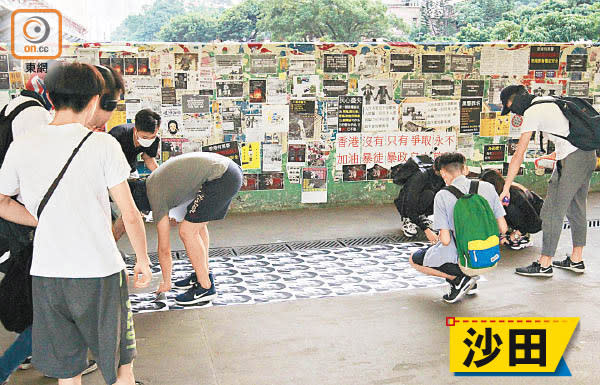 市民在港鐵沙田站外地上，貼上何君堯照片的單張。（袁以諾攝）