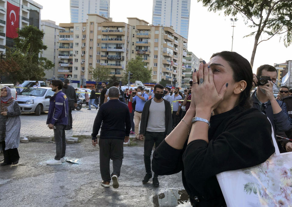 A woman watches as rescue workers try to save people trapped in the debris of a collapsed building, in Izmir, Turkey, Friday, Oct. 30, 2020. A strong earthquake struck Friday in the Aegean Sea between the Turkish coast and the Greek island of Samos, killing several people and injuring hundreds amid collapsed buildings and flooding, officials said.(AP Photo/Ismail Gokmen)