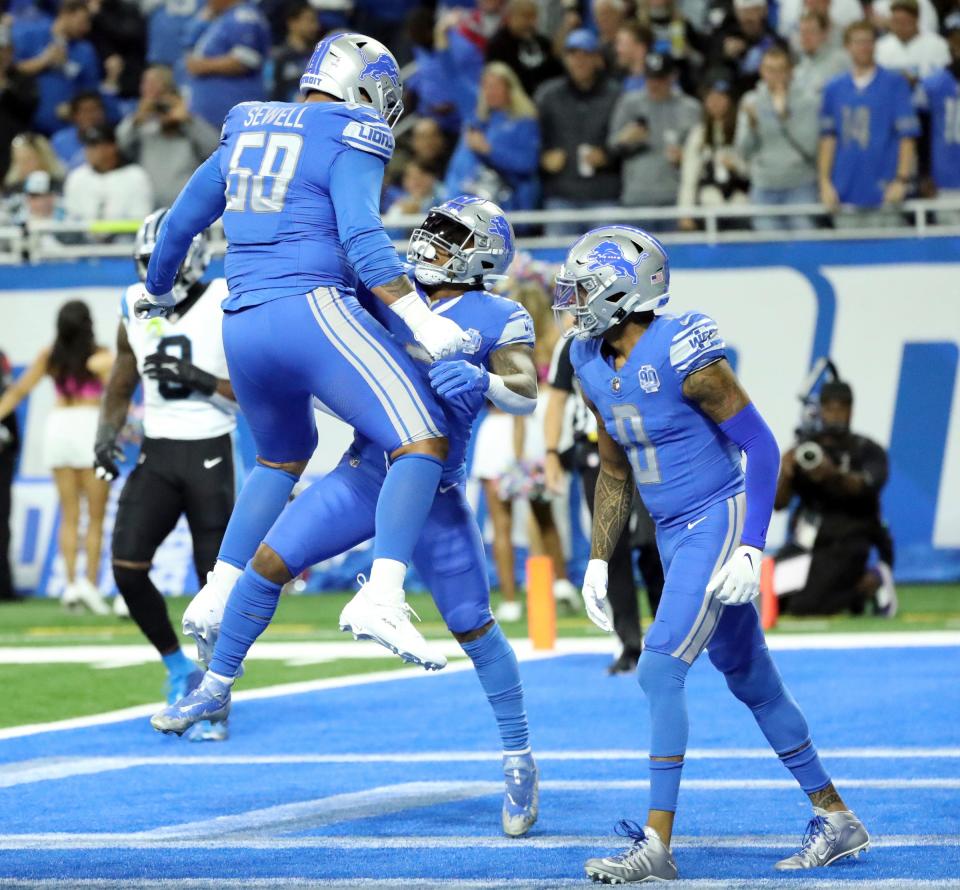 Detroit Lions offensive tackle Penei Sewell (58) and running back David Montgomery (5) celebrate after a touchdown against the Carolina Panthers during first-half action at Ford Field in Detroit on Sunday, Oct, 8, 2023.