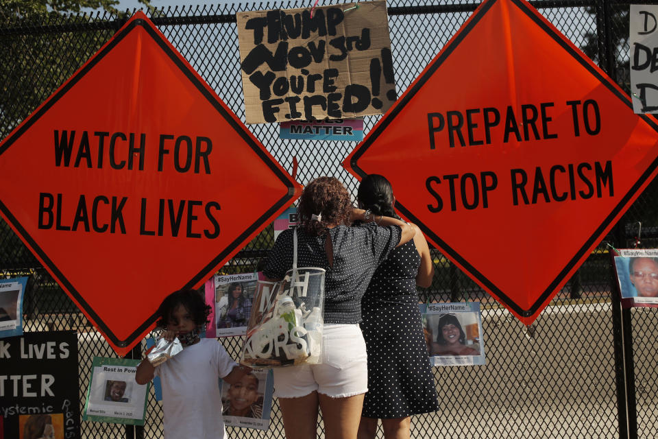 Women peek through a security fence at the White House from a section of 16th Street that's been renamed Black Lives Matter Plaza, Saturday, July 4, 2020, in Washington.(AP Photo/Maya Alleruzzo)