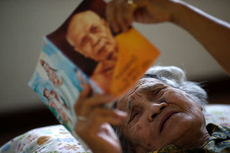 An elderly woman reads a Dhamma book during a physical therapy session at Bangkhae Home Foundation in Bangkok, Thailand, April 27, 2016. REUTERS/Athit Perawongmetha