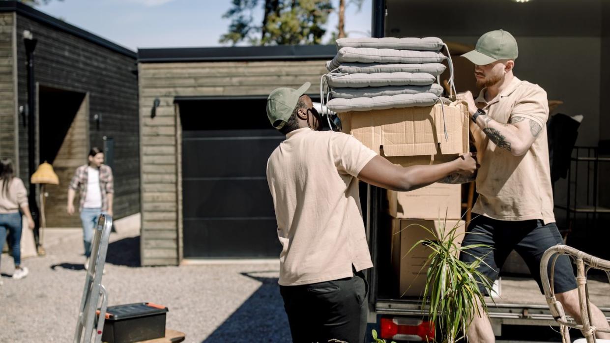 delivery men picking cardboard boxes from truck during sunny day