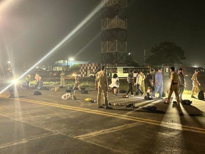Police officers and passengers on the runway with luggage strewn about on the tarmac at Ahmedabad Airport in June 2024.