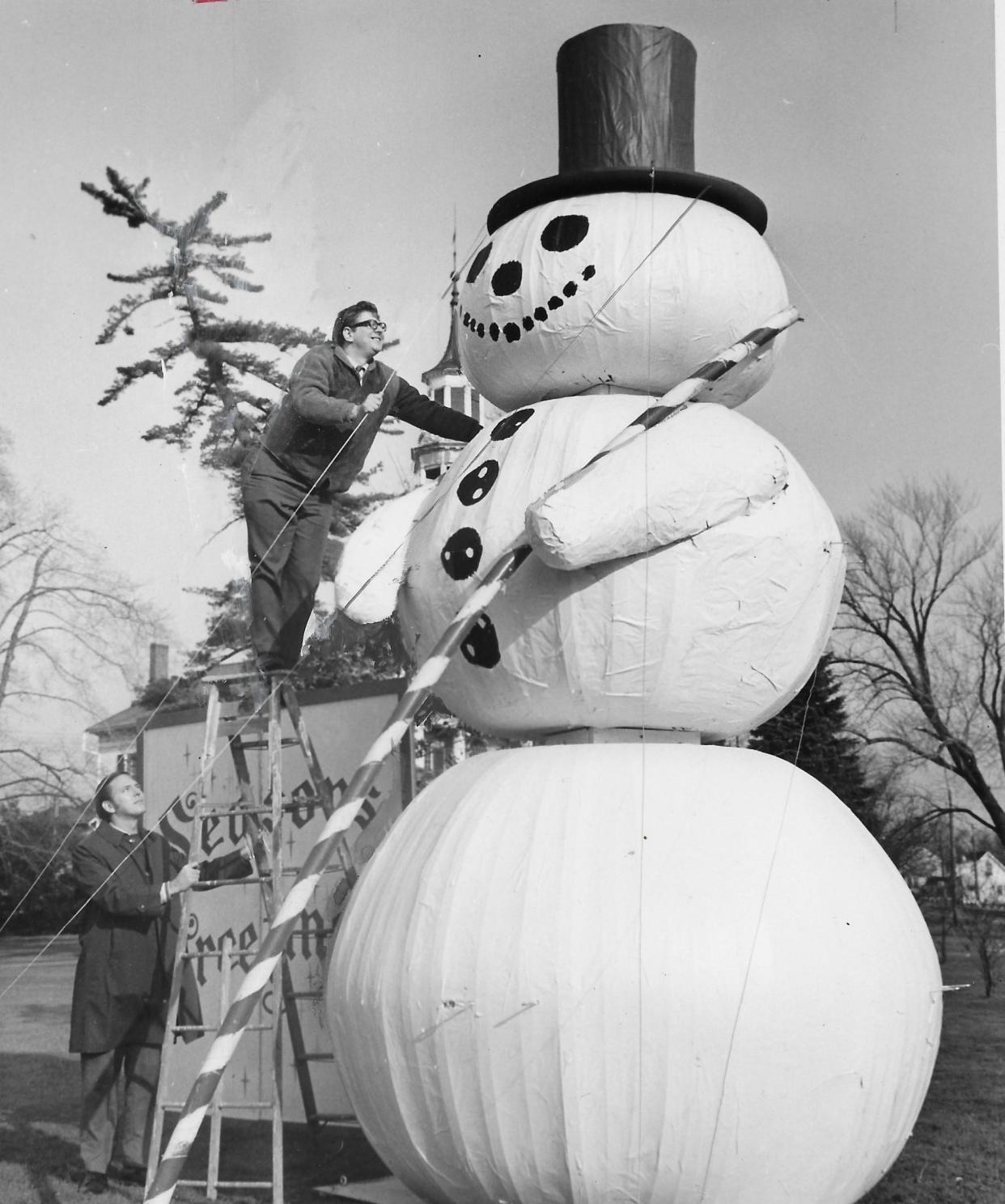 Tallmadge Jaycees member Tony Paduchik scales a ladder to inspect an 18-foot snowman at Tallmadge Circle on Dec. 9, 1970.