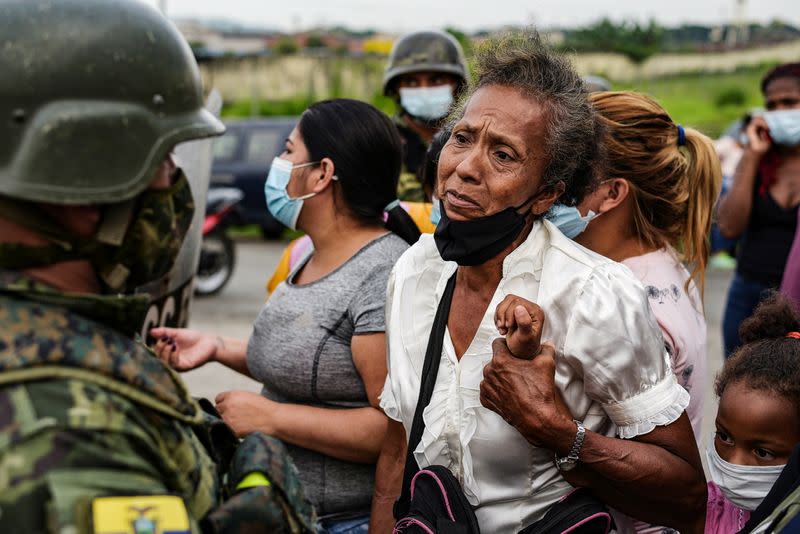 A woman holds on to a child while standing outside a prison where inmates were killed during a riot that the government described as a concerted action by criminal organisations, in Guayaquil