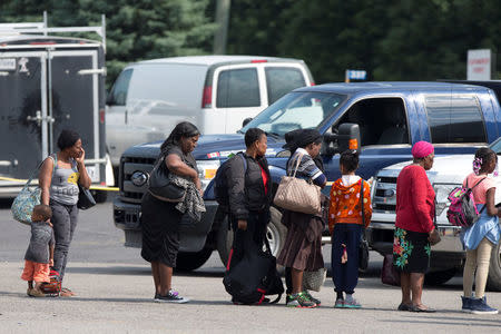 A group of asylum seekers wait to be processed after being escorted from their tent encampment to the Canada Border Services in Lacolle, Quebec, Canada August 11, 2017. REUTERS/Christinne Muschi