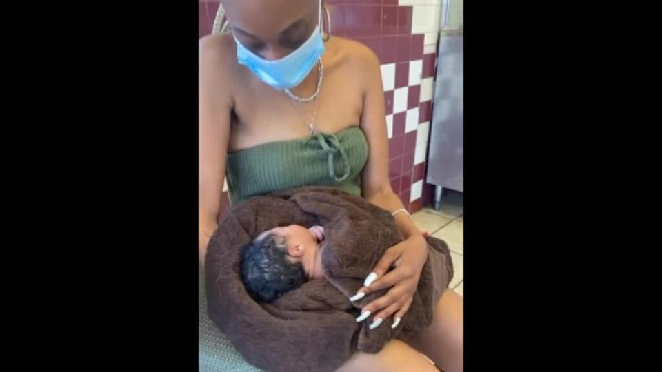 Jersey City restaurant customer Alease Scott holds the newborn girl a 14-year-old left with her Wednesday. (YouTube)