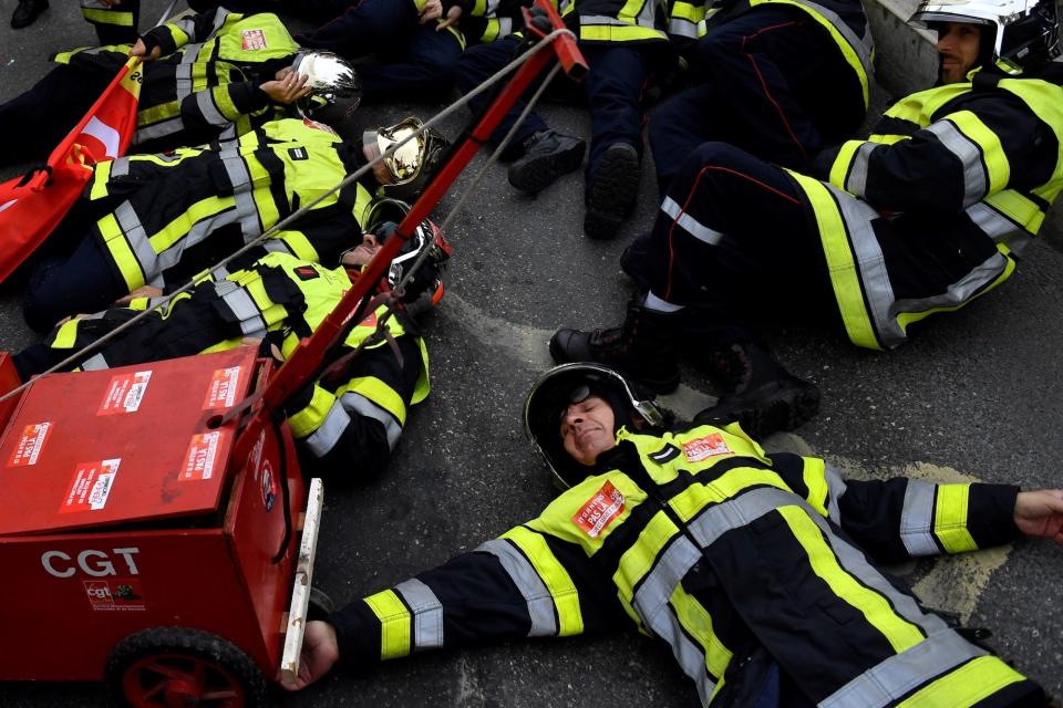 Firefighters lay on the ground as they take part in a demonstration to protest against the pension overhauls, in Marseille, southern France, on December 5, 2019 as part of a national general strike.