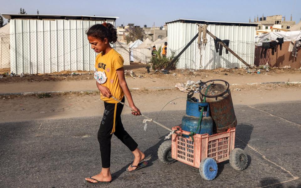 A girl pulls a cart loaded with gas cylinders along a street in Rafah in southern Gaza