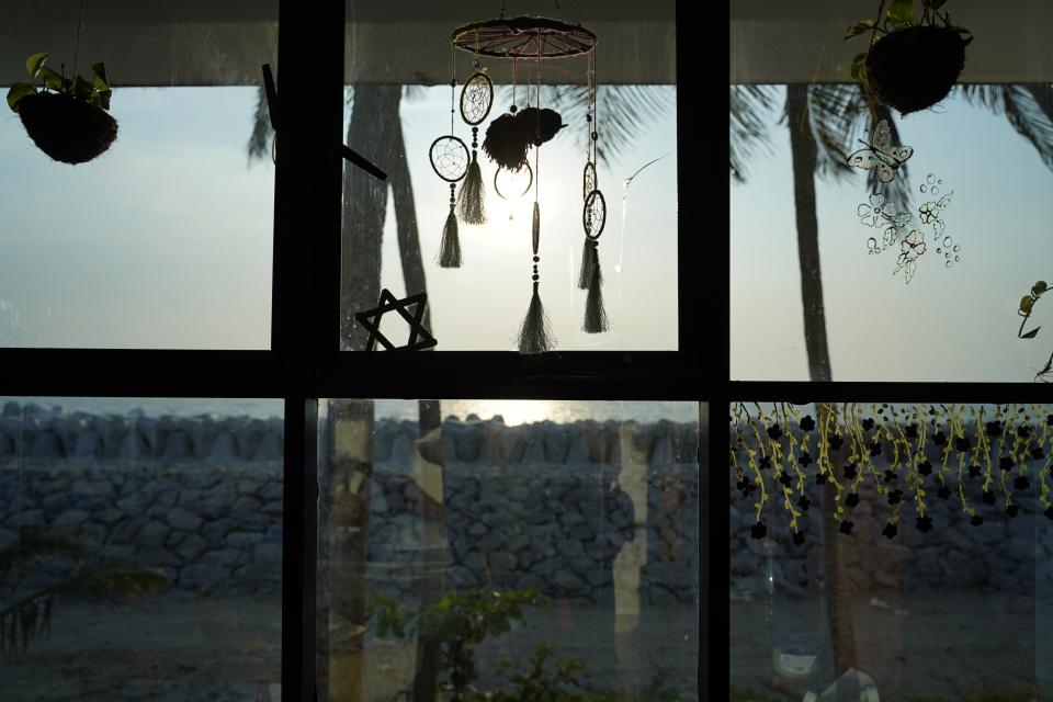 Dreamcatchers hang from the room of Hima Rose with a new sea wall in the background in Kochi, Kerala state, India, March 4, 2023. Rose said that after Cyclone Tauktae, she welcomed neighbors to her home, providing them shelter and food for several days. (AP Photo)