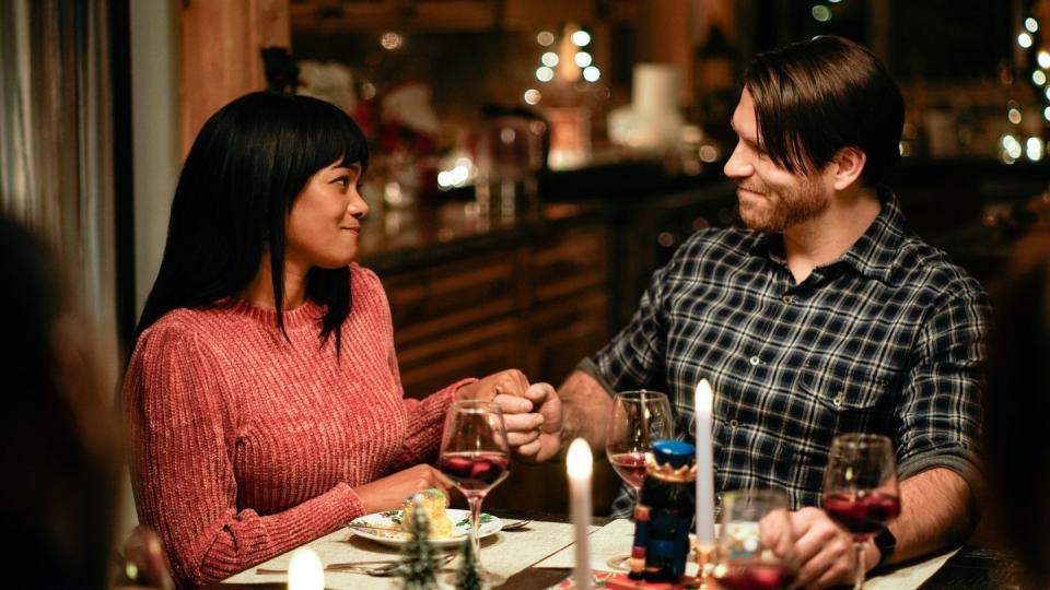 woman and man holding hands at table