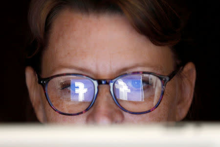 The Facebook logo is reflected on a woman's glasses in this photo illustration taken June 3, 2018. REUTERS/Regis Duvignau/Illustration