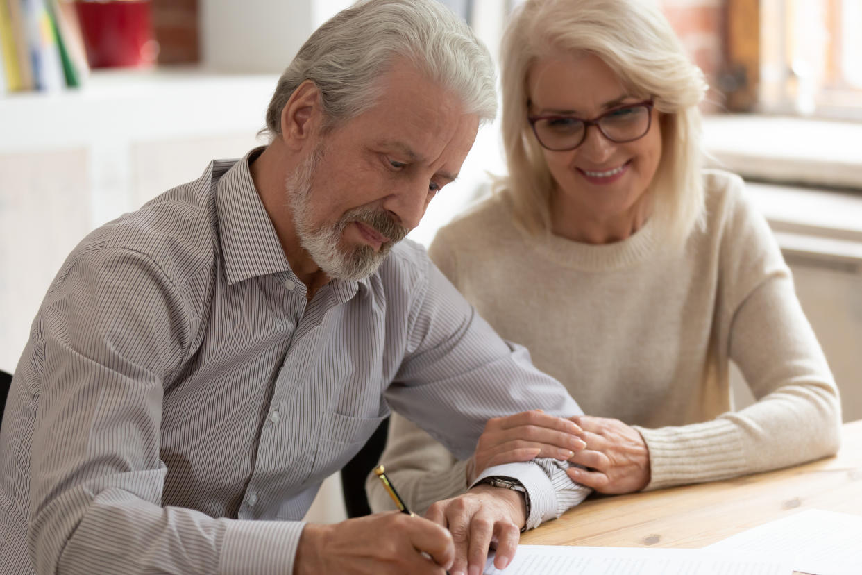 Happy older family couple husband and wife sign legal paper insurance contract write will testament, senior clients customers put signature on business document make financial deal take bank loan