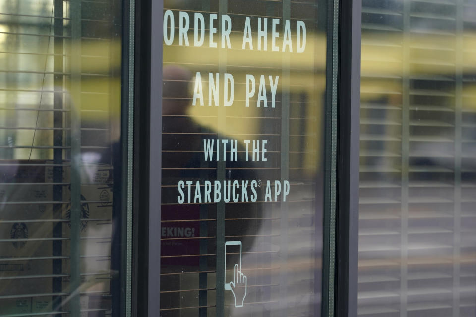 A sign on a window at a Starbucks Coffee store in south Seattle reads "Order ahead and pay with the Starbucks app," Tuesday, Oct. 27, 2020. Starbucks saw faster-than-expected recovery in the U.S. and China in its fiscal fourth quarter, giving it confidence as it heads into the holiday season. (AP Photo/Ted S. Warren)