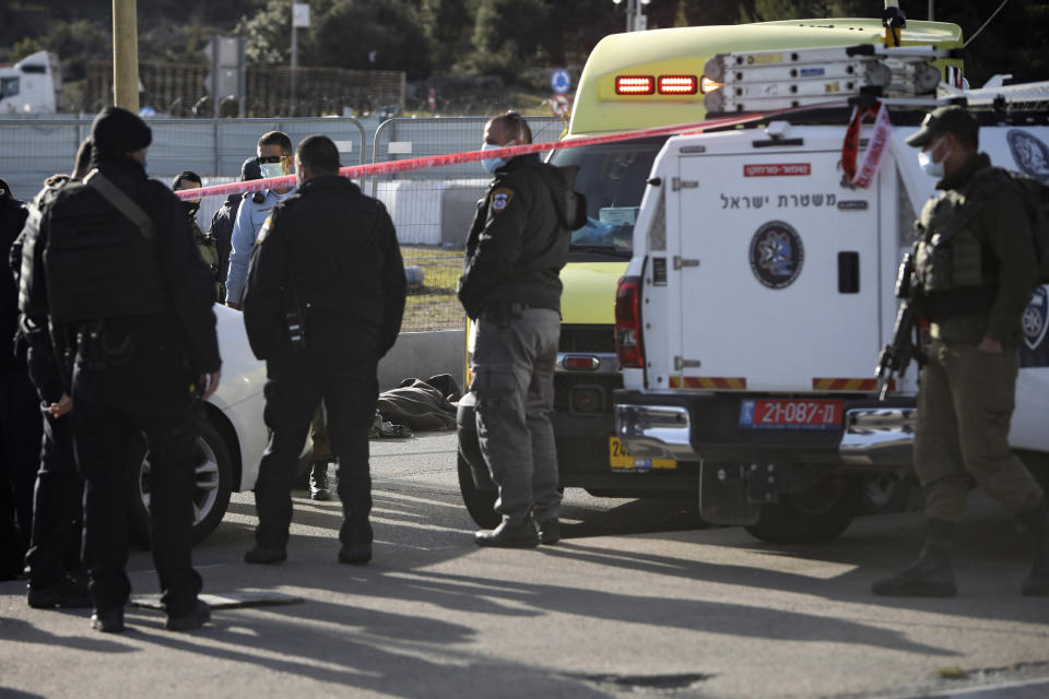 Israeli soldiers stand next to the body of a Palestinian at the scene of an attack near the West Bank settlement of Gush Etzion, Sunday, Jan. 31, 2021. An Israeli soldier on Sunday shot and killed a Palestinian suspected of attempting an attack at a West Bank junction south of Bethlehem, the military said. (AP Photo/Mahmoud Illean)