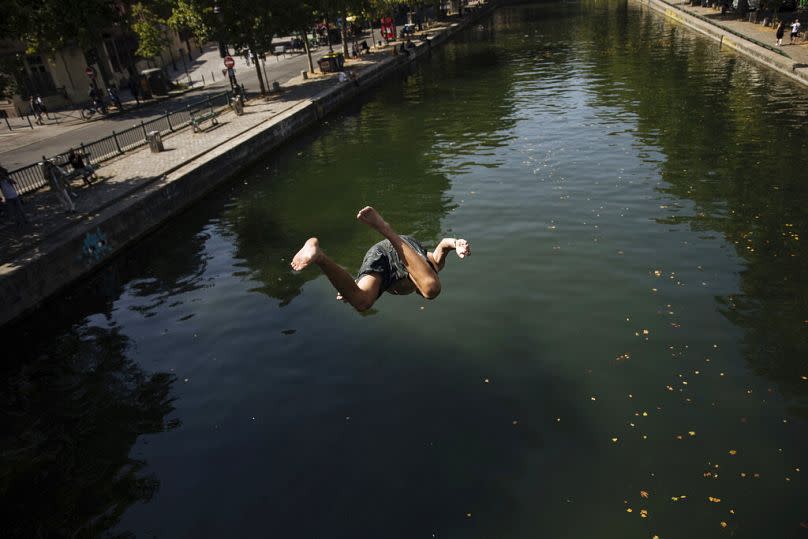 Kids jump from a bridge to swim in the Canal St Martin, during a heatwave in Paris, July 2022