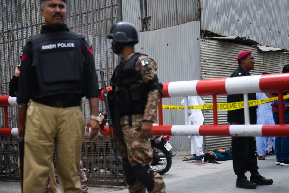 EDITORS NOTE: Graphic content / Police and paramilitary soldiers stand guard near a body of an alleged gunman at the main entrance of the Pakistan Stock Exchange building in Karachi on June 29, 2020. - Gunmen attacked the Pakistan Stock Exchange in Karachi on June 29, with four of the assailants killed, police said. (Photo by Asif HASSAN / AFP) (Photo by ASIF HASSAN/AFP via Getty Images)