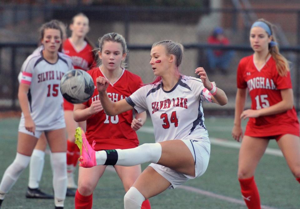 Silver Lake's Alli Powderly, center, kicks the ball away from Hingham's Carolyn Downey, left, during the first round of the Div. 2 girls soccer state tournament at Hingham High School, Sunday, Nov. 5, 2023.
