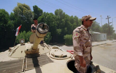 Iraqi soldiers sit on a tank at the entry of Zubair oilfield after a rocket struck  - Credit: REUTERS/Essam Al-Sudani