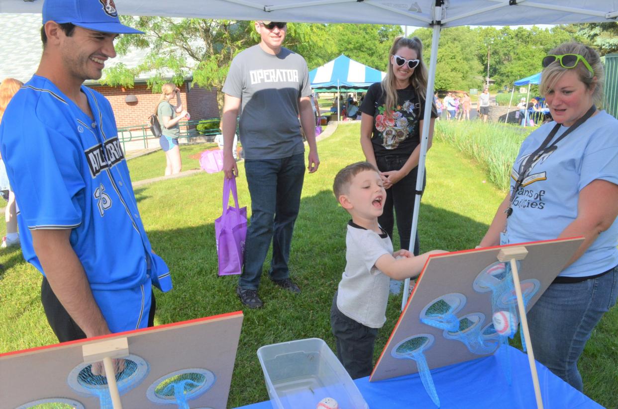 Battle Creek Battle Jacks player Jackson Braden watches as Isaac Stokes, 6, of Battle Creek enjoys some of the carnival games at the kickoff event for the Willard Library Summer Reading Program at the Helen Warner Branch on Tuesday.