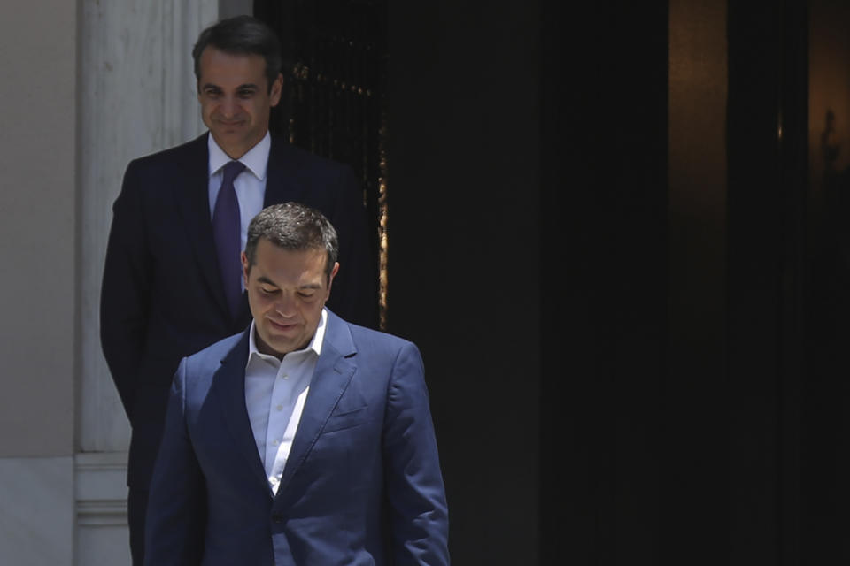 Greece's newly-elected prime minister Kyriakos Mitsotakis, background, looks on as outgoing prime minister Alexis Tsipras, leaves the Maximos Mansion in Athens, Monday, July 8, 2019. Mitsotakis' New Democracy party won 39.8% of the vote, giving him 158 seats in the 300-member parliament, a comfortable governing majority. (AP Photo/Petros Giannakouris)