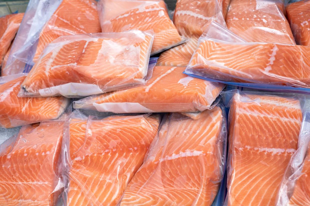 Closeup view of a pile of pieces of raw salmon packaged in small plastic bags on farmers market stand