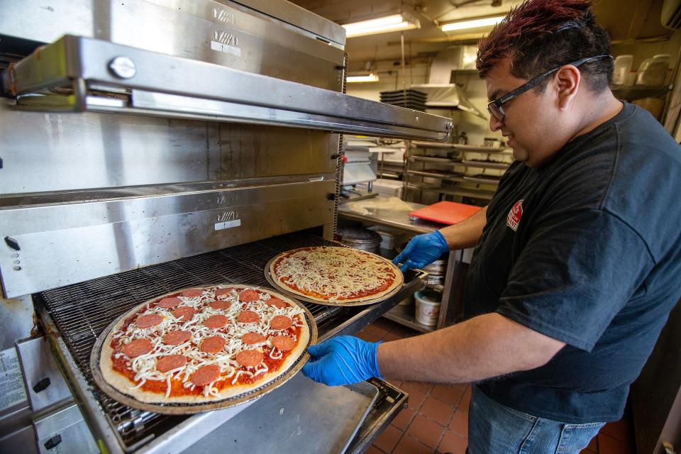 Abraham Jimenez of Neptune City, pie room manager, places two pizzas in the conveyor belt oven at Vic's Italian Restaurant in Bradley Beach Wednesday, July 5, 2023.