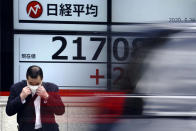 A man adjusts a mask in front an electronic stock board showing Japan's Nikkei 225 index at a securities firm in Tokyo Thursday, May 28, 2020. Asian stocks are mixed after an upbeat open, as hopes for an economic rebound from the coronavirus crisis were dimmed by tensions between the U.S. and China over Hong Kong and other issues. (AP Photo/Eugene Hoshiko)