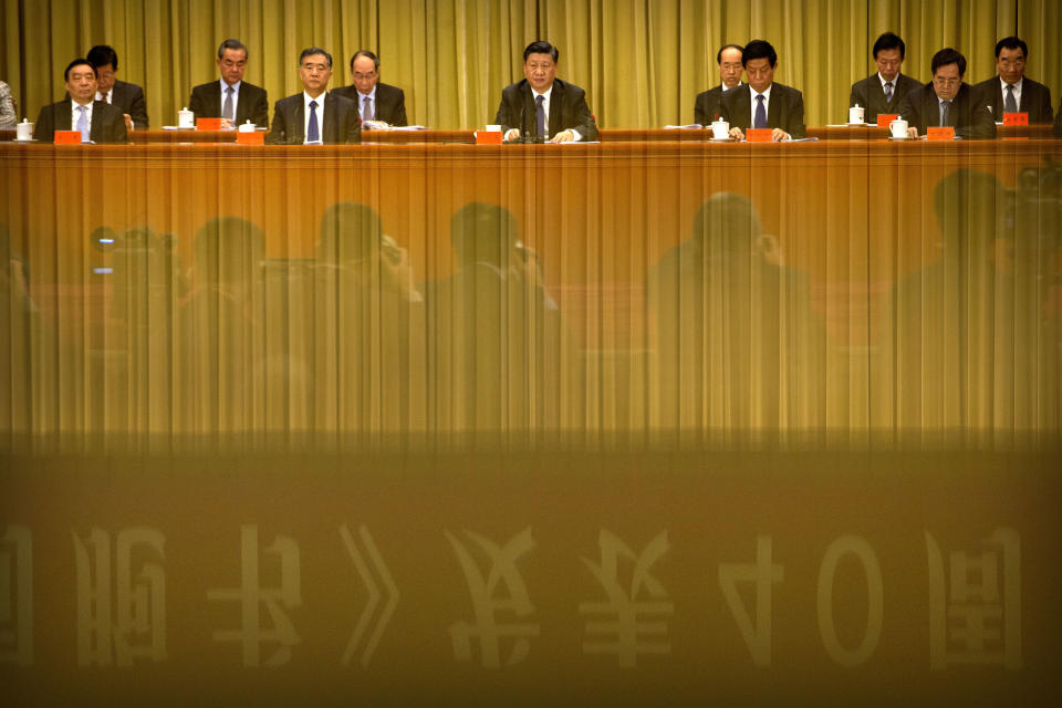 In this Wednesday, Jan. 2, 2019, file photo, a banner is reflected in a polished surface as Chinese President Xi Jinping, center, speaks during an event to commemorate the 40th anniversary of the Message to Compatriots in Taiwan at the Great Hall of the People in Beijing, Wednesday, Jan. 2, 2019. Xi urged both sides to reach an early consensus on the unification of China and Taiwan and not leave the issue for future generations. (AP Photo/Mark Schiefelbein, Pool, File)