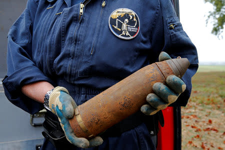A deminer from a bomb-disposal unit holds an unexploded shell recovered in a field in Jametz, close to WWI battlefields, near Verdun, France, October 24, 2018 before the centenial commemoration of the First World War Armistice Day. REUTERS/Pascal Rossignol