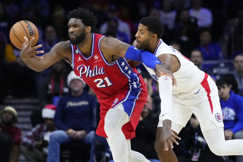 Philadelphia 76ers' Joel Embiid, left, tries to hang onto the ball against Los Angeles Clippers' Paul George during the first half of an NBA basketball game, Friday, Dec. 23, 2022, in Philadelphia. (AP Photo/Matt Slocum)