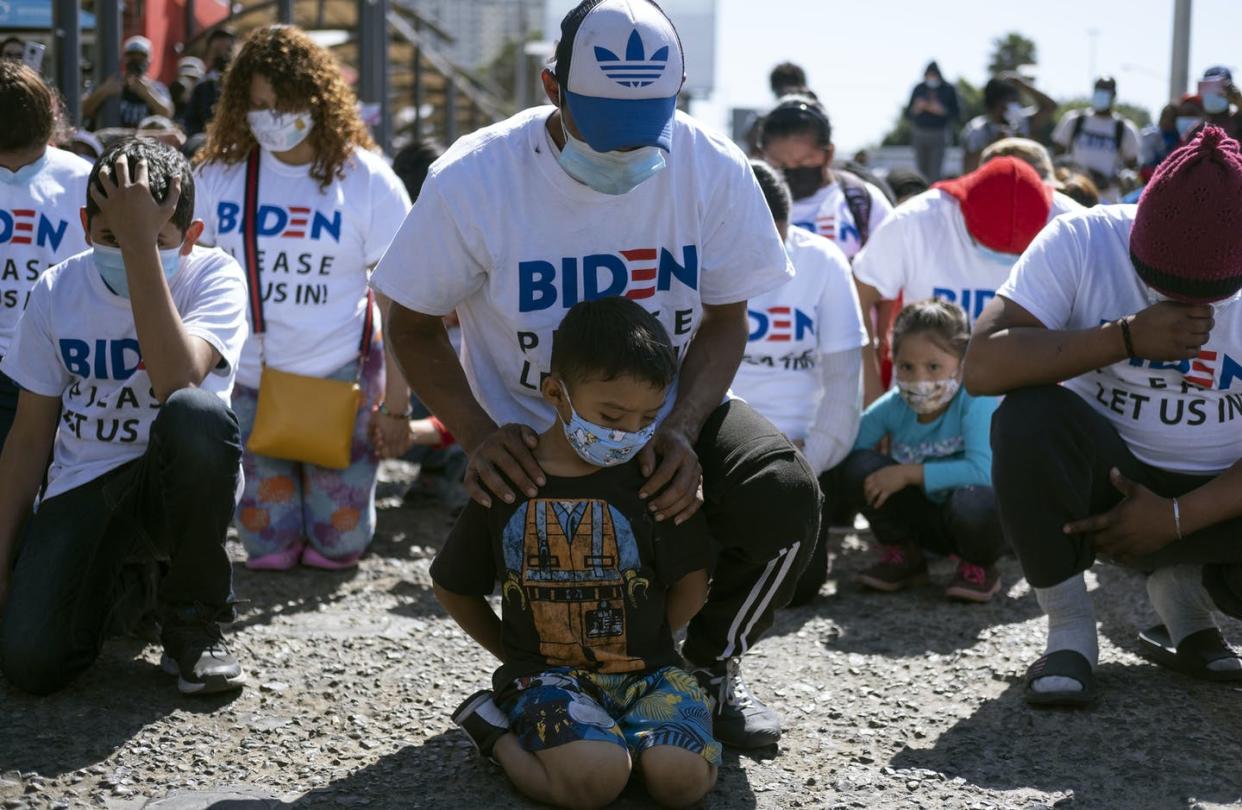 <span class="caption">Migrants pray at a March 2 demonstration at San Ysidro crossing port in Tijuana, Mexico, to demand clearer U.S. migration policies.</span> <span class="attribution"><a class="link " href="https://www.gettyimages.com/detail/news-photo/yadiel-garcia-and-his-father-fabricio-from-honduras-kneel-news-photo/1231478713?adppopup=true" rel="nofollow noopener" target="_blank" data-ylk="slk:Guillermo Arias/AFP via Getty Images;elm:context_link;itc:0;sec:content-canvas">Guillermo Arias/AFP via Getty Images</a></span>