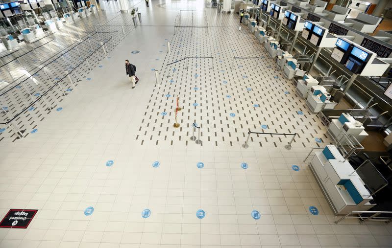 FILE PHOTO: A passenger walks past empty check-in counters at Cape Town International Airport