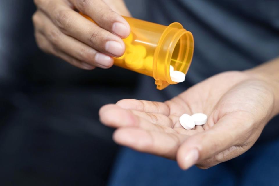 Person spilling pills out medicine bottle