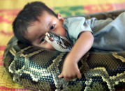 El niño camboyano de 3 años Oeun Sambat abraza a su mejor amiga, una pitón de 13.1 pies de largo llamada Chamreun or "Suertuda" en la villa de Sit Tbow en mayo del 2003. REUTERS/Chor Sokunthea