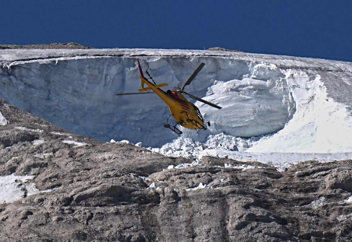 A rescue helicopter flies over the glacier (AFP via Getty Images)