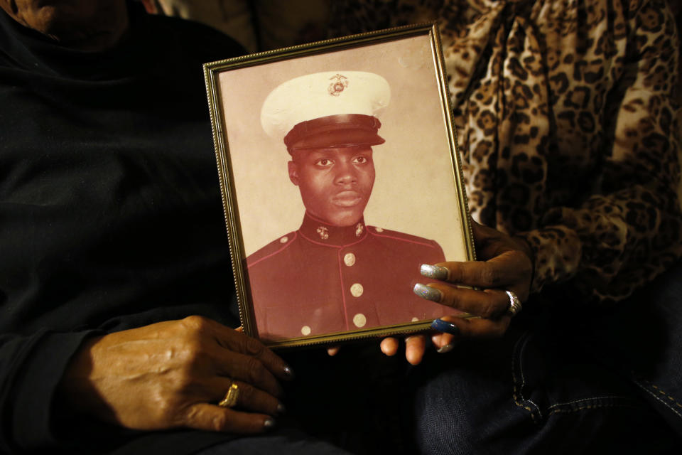 In this March 12, 2014 photo, a picture of Jerome Murdough is held by his mother Alma Murdough left, and sister Cheryl Warner at Alma Murdough's home in the Queens borough of New York. Jerome Murdough, a mentally ill, homeless former Marine arrested for sleeping in the roof landing of a New York City public housing project during one of the coldest recorded winters in city history, died last month in a Rikers Island jail cell that multiple city officials say was at least 100 degrees when his body was discovered. Murdough, 56, was found dead in his cell in a mental observation unit in the early hours of Feb. 15, after excessive heat, believed to be caused by an equipment malfunction, redirected it’s flow to his upper-level cell, the officials said. (AP Photo/Jason DeCrow)