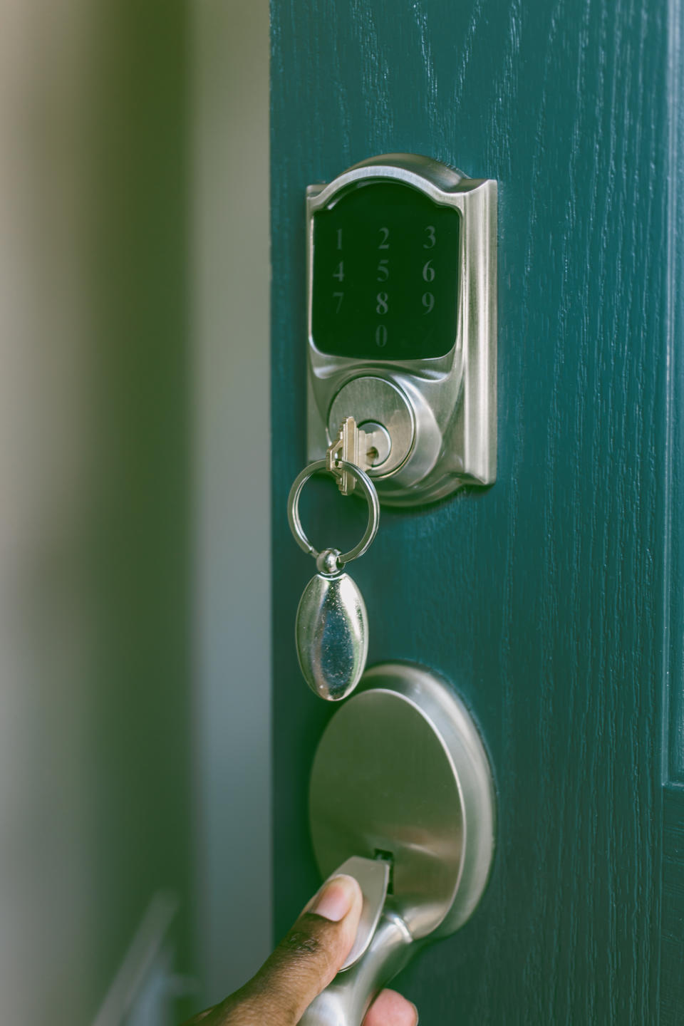 Person's hand using a keyless entry pad with a keychain hanging from the knob