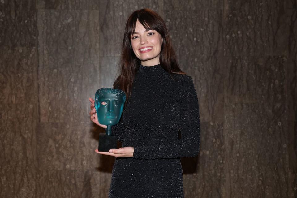 emma mackey holds the rising star trophy backstage at the bafta film awards