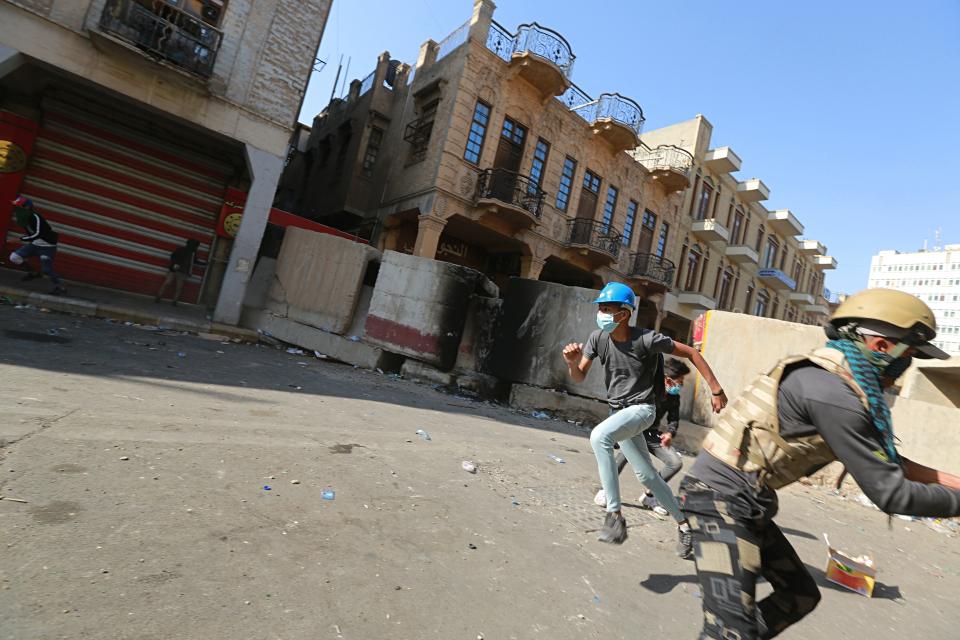 Protesters run for cover during clashes with Iraqi security forces in al-Rashid Street, Baghdad, Iraq, Sunday, Nov. 17, 2019. (AP Photo/Hadi Mizban)