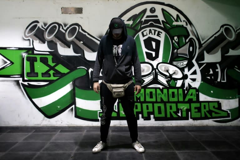 A member of Gate-9, a fan group supporting Nicosia's AC Omonia football team, stands next to a club sign in the Cypriot capital