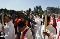 With Notre Dame cathedral in background, religious officials carry the cross during the Good Friday procession, Friday, April 19, 2019 in Paris. Top French art conservation officials say the works inside Notre Dame suffered no major damage in the fire that devastated the cathedral, and the pieces have been removed from the building for their protection.(AP Photo/Francois Mori)