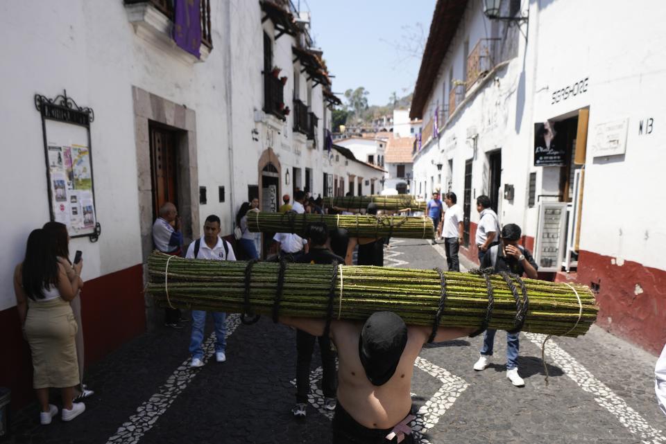 Penitents carry a bundle of thorny branches during a Holy Week procession in Taxco, Mexico, Thursday, March 28, 2024. In traditional processions that last from Thursday evening into the early morning hours of Friday, hooded penitents drag chains and shoulder the thorny bundles through the streets, as some flog themselves with nail-studded whips meant to bring them closer to God. (AP Photo/Fernando Llano)