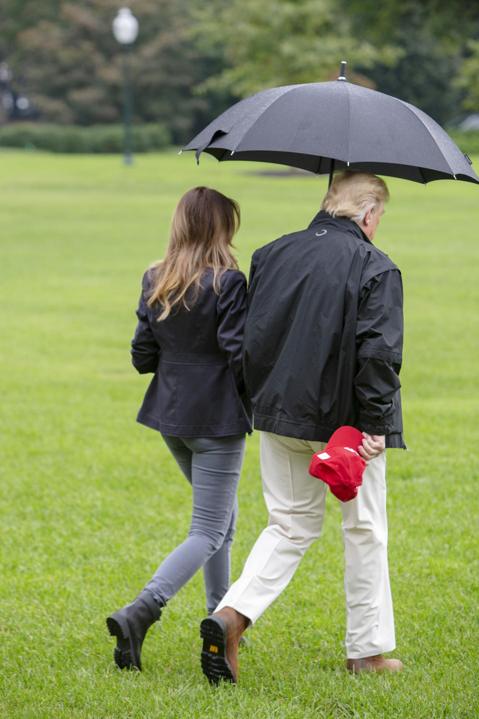The President continued to only cover himself with the umbrella as the pair walked towards their awaiting helicopter. Source: Getty