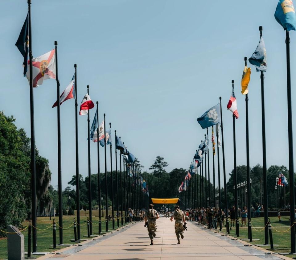 US Army soldiers run toward the finish line of a race course lined with flags