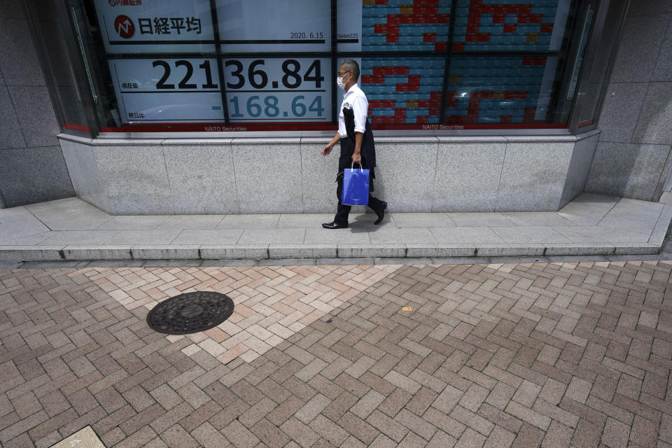 A man walks past an electronic stock board showing Japan's Nikkei 225 index at a securities firm in Tokyo Monday, June 15, 2020. Asian shares were mostly lower Monday on concern over a resurgence of coronavirus cases and pessimism after Wall Street posted its worst week in nearly three months. (AP Photo/Eugene Hoshiko)