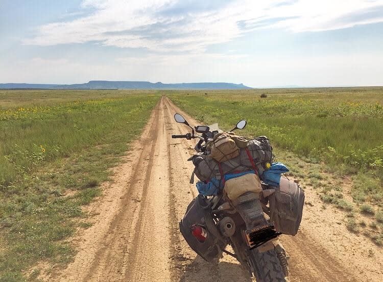 a motorcycle saddled with packs on a dirt road at the border of New Mexico and Colorado in the US