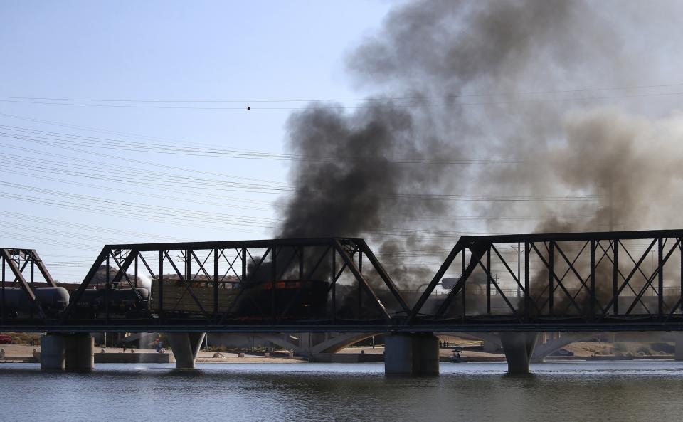 A derailed freight train burns on a bridge spanning Tempe Town Lake Wednesday, July 29, 2020, in Tempe, Ariz. Officials say a freight train traveling on the bridge that spans a lake in the Phoenix suburb has derailed, setting the bridge ablaze and partially collapsing the structure. (AP Photo/Ross D. Franklin)