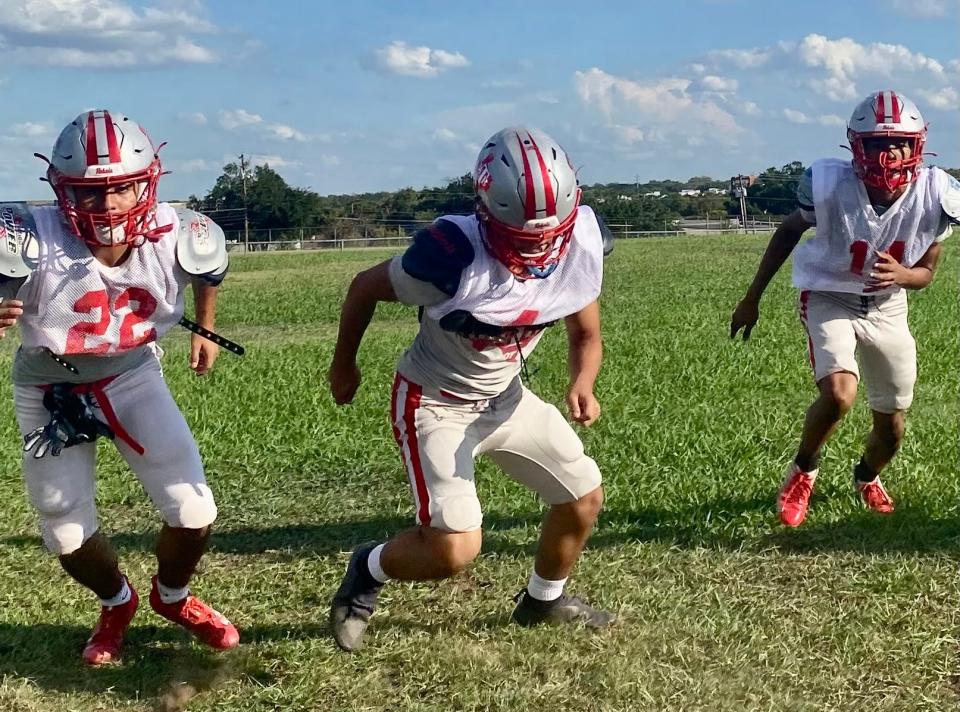 From left to right, Raymond Chavez, Leo Garcia and Ronald Sauls run backpedaling and cutting drills at football practice. The Rebels are looking for their first winning record in 10 years.