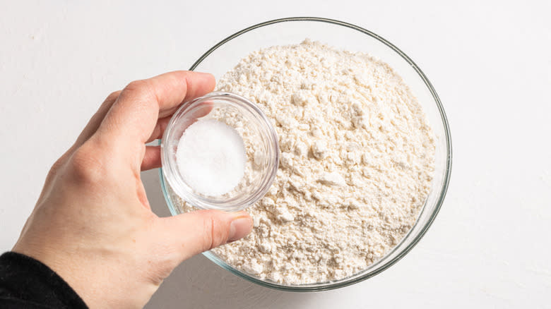 Adding salt to a bowl with flour